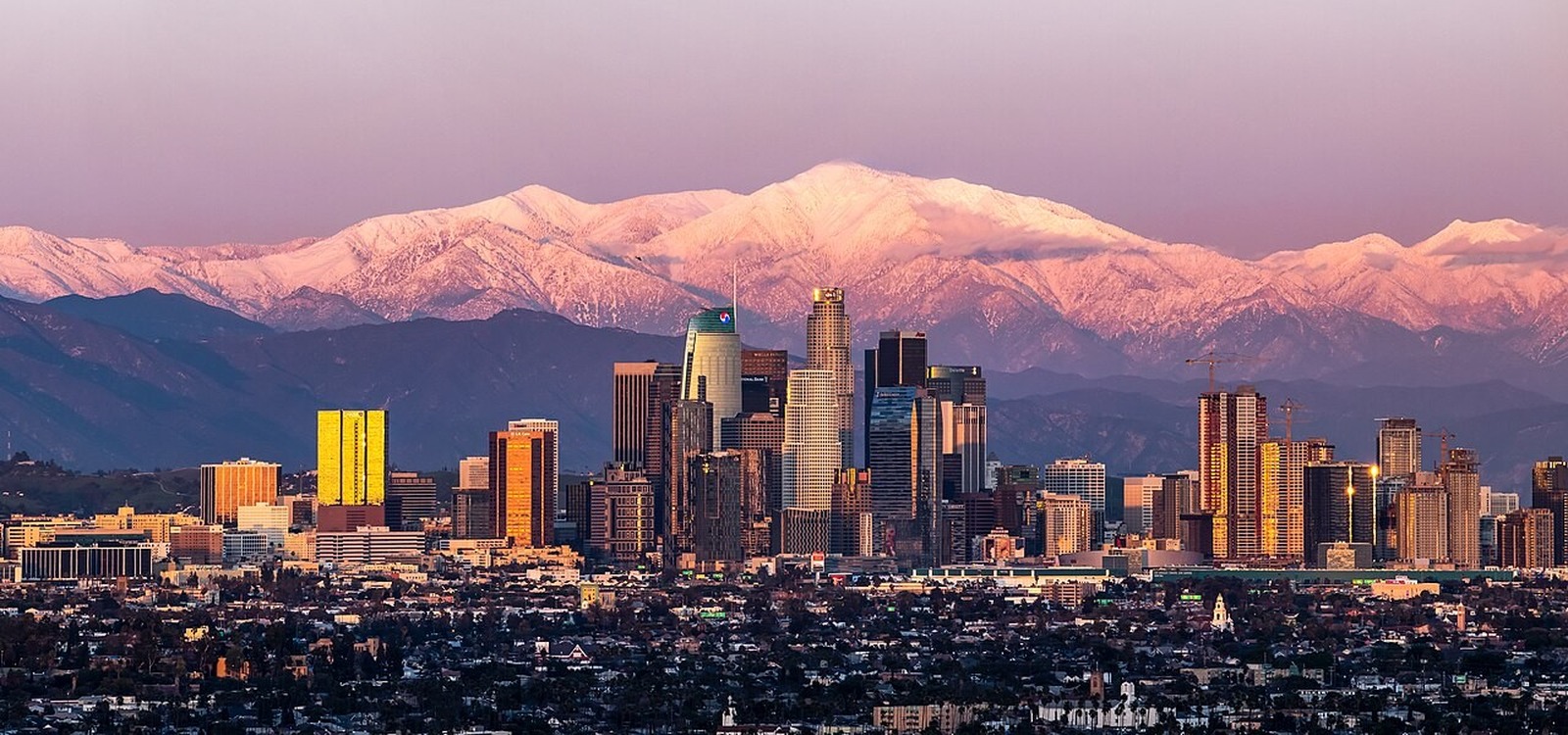 Downtown Los Angeles skyscrapers beneath snow-capped San Gabriel Mountains